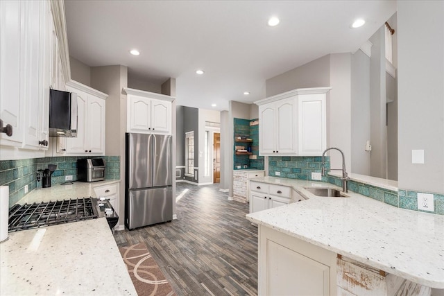 kitchen with dark wood-style flooring, a peninsula, stainless steel appliances, white cabinetry, and a sink