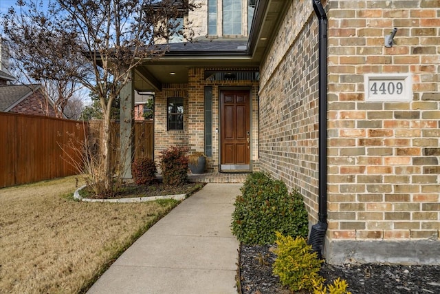 doorway to property with brick siding and fence