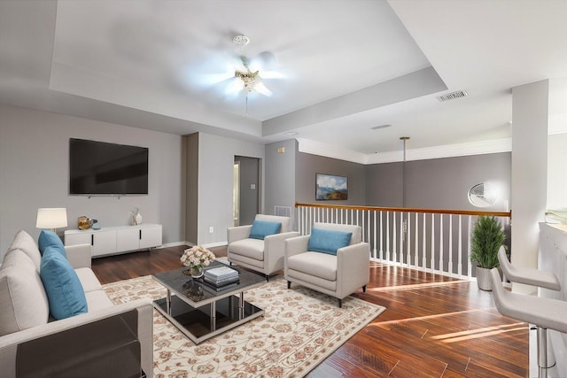 living area featuring baseboards, visible vents, a raised ceiling, and wood finished floors