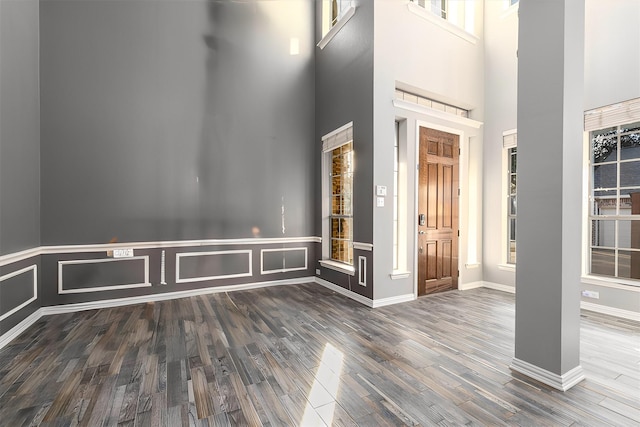 entryway featuring a towering ceiling, baseboards, and wood finished floors