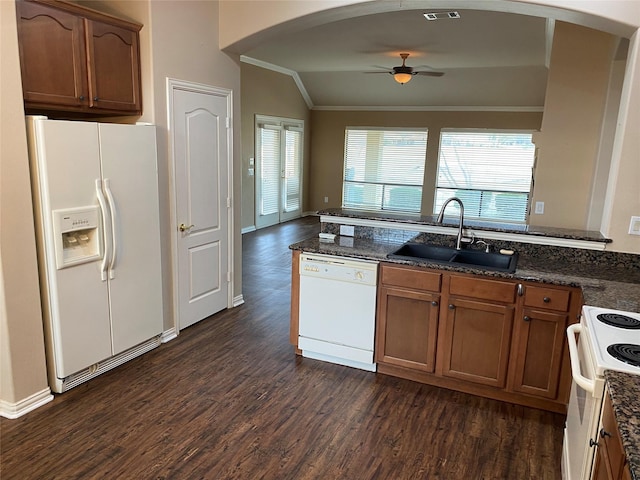 kitchen with vaulted ceiling, sink, dark stone counters, dark wood-type flooring, and white appliances