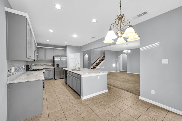 kitchen with gray cabinets, decorative light fixtures, a chandelier, stainless steel appliances, and a center island with sink