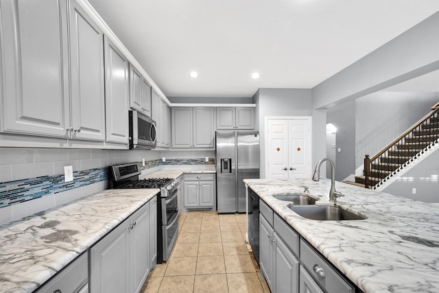 kitchen with light tile patterned flooring, stainless steel appliances, sink, and gray cabinetry