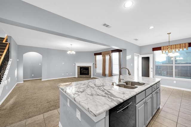 kitchen with dishwasher, sink, gray cabinetry, a chandelier, and a kitchen island with sink