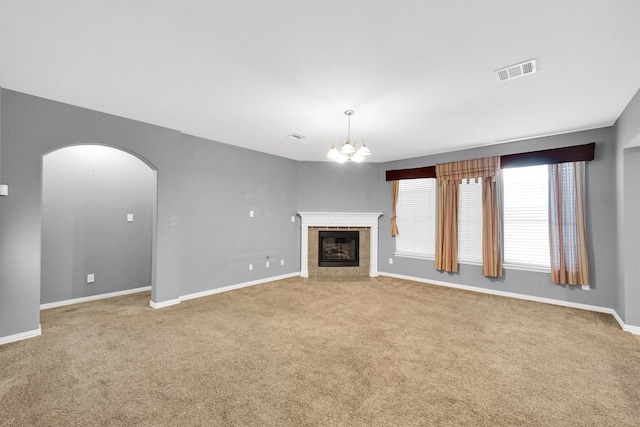 unfurnished living room with light carpet, a tile fireplace, and a chandelier