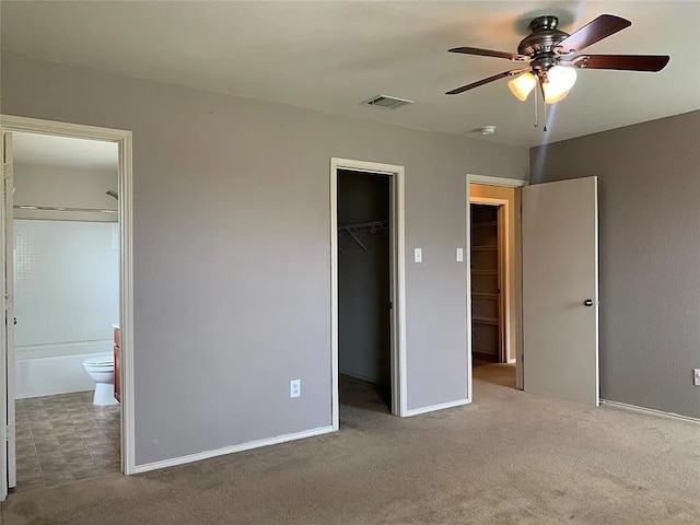 unfurnished bedroom with a closet, connected bathroom, a spacious closet, and carpet