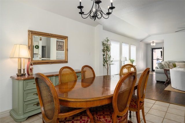 tiled dining area featuring lofted ceiling and an inviting chandelier