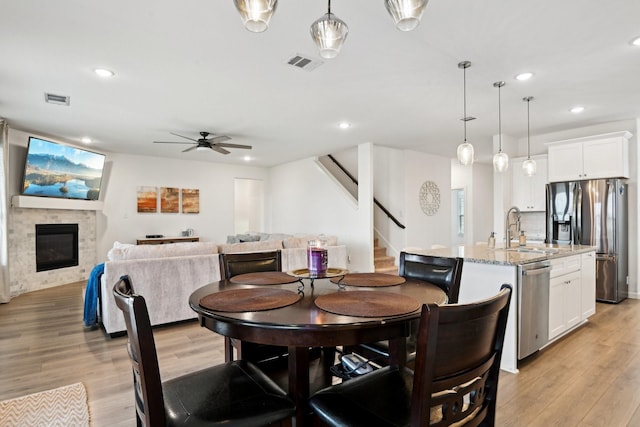 dining room featuring sink, ceiling fan, and light wood-type flooring