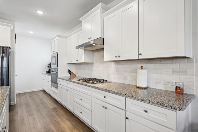 kitchen featuring white cabinetry, built in microwave, wood-type flooring, and light stone countertops