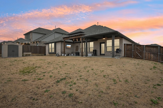 back house at dusk with a storage unit and a patio area