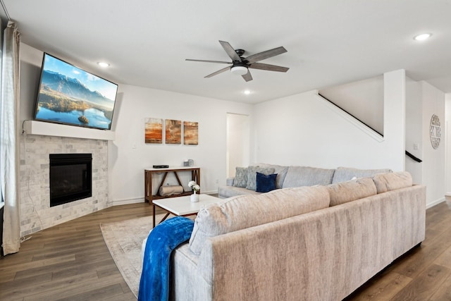 living room with dark wood-type flooring, a large fireplace, and ceiling fan