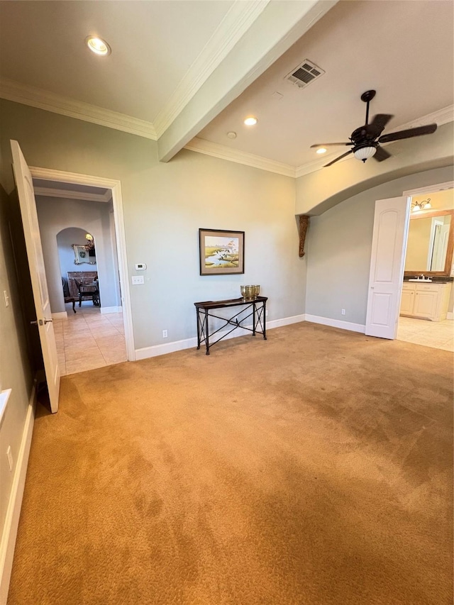 empty room with crown molding, light colored carpet, visible vents, and arched walkways