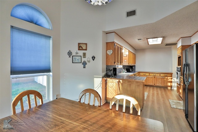 dining space with sink, a textured ceiling, and light hardwood / wood-style flooring