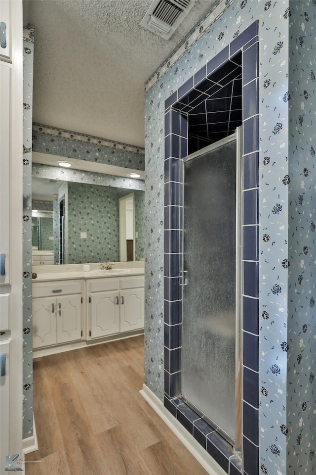 bathroom featuring hardwood / wood-style flooring, vanity, a shower, and a textured ceiling