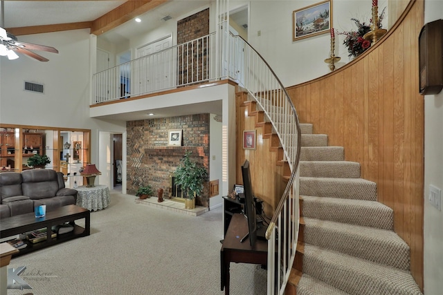 living room with high vaulted ceiling, wood walls, carpet flooring, ceiling fan, and beam ceiling