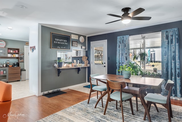 dining room featuring crown molding, ceiling fan, indoor bar, and light hardwood / wood-style flooring