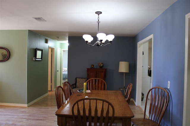 dining area with an inviting chandelier and light hardwood / wood-style flooring