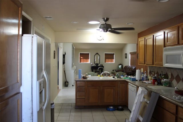 kitchen featuring white appliances, kitchen peninsula, sink, and decorative backsplash