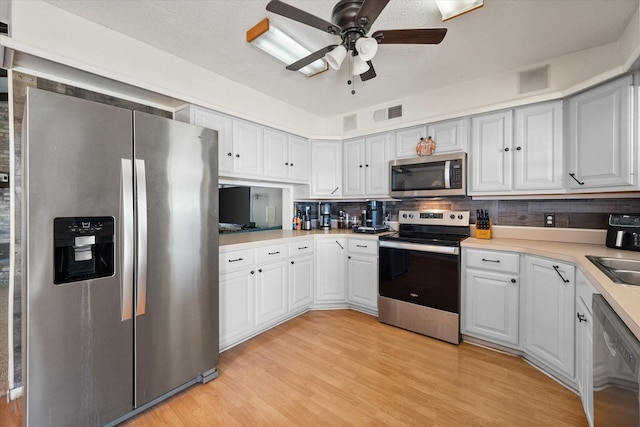 kitchen with stainless steel appliances, white cabinetry, sink, and light wood-type flooring