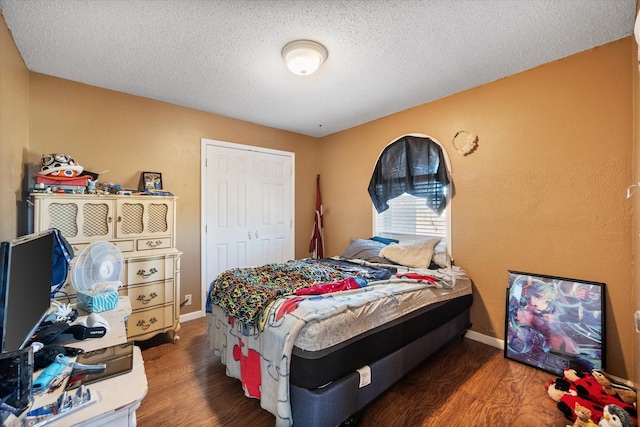 bedroom with dark wood-type flooring, a closet, and a textured ceiling