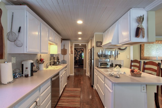 kitchen with appliances with stainless steel finishes, white cabinetry, sink, a kitchen bar, and dark wood-type flooring