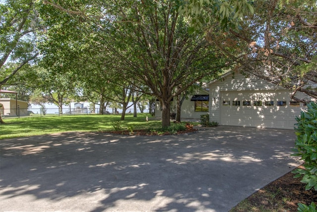 view of property hidden behind natural elements with a garage and a front yard