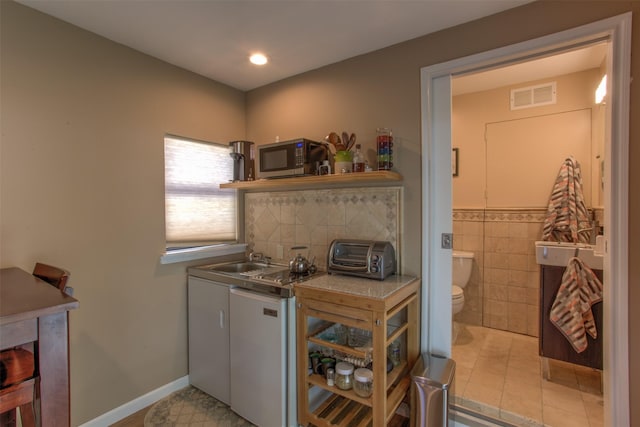 laundry room featuring light tile patterned flooring, sink, and tile walls