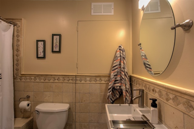 bathroom with tile walls, sink, and toilet