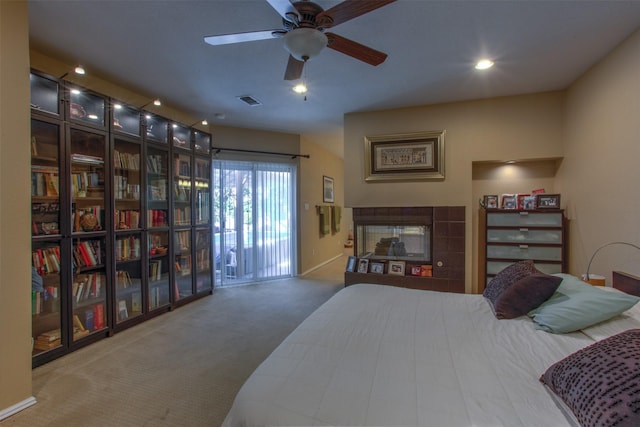 carpeted bedroom featuring ceiling fan, access to exterior, and a tile fireplace