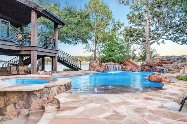 view of swimming pool with an in ground hot tub, a water slide, and a patio area