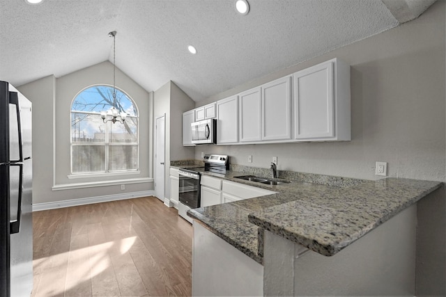 kitchen with white cabinetry, vaulted ceiling, appliances with stainless steel finishes, kitchen peninsula, and pendant lighting