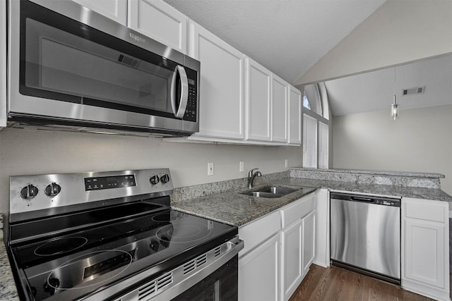 kitchen with sink, vaulted ceiling, white cabinets, and appliances with stainless steel finishes