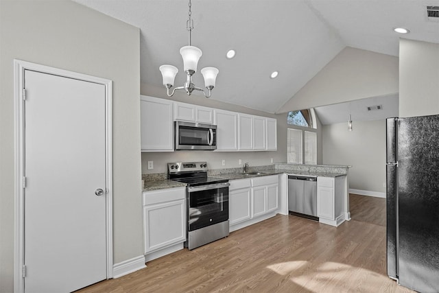 kitchen featuring white cabinetry, vaulted ceiling, hanging light fixtures, light wood-type flooring, and appliances with stainless steel finishes