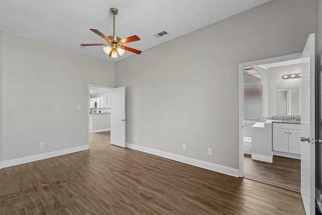 unfurnished bedroom featuring dark hardwood / wood-style flooring, connected bathroom, sink, and ceiling fan