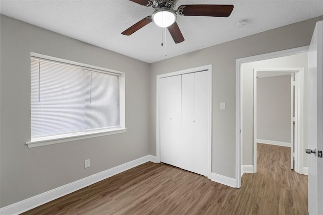 unfurnished bedroom featuring hardwood / wood-style flooring, ceiling fan, a closet, and a textured ceiling