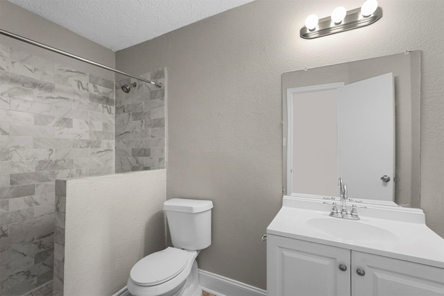 bathroom featuring tiled shower, vanity, toilet, and a textured ceiling