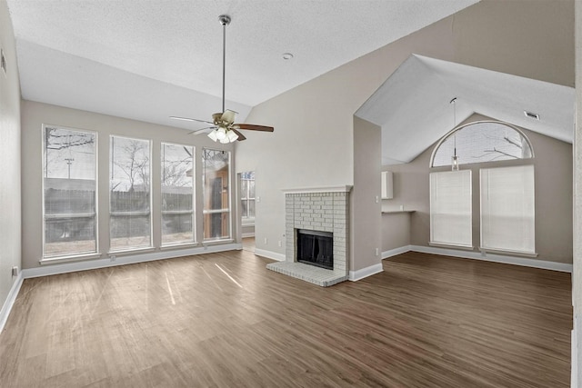 unfurnished living room featuring dark hardwood / wood-style floors, a fireplace, lofted ceiling, ceiling fan, and a textured ceiling