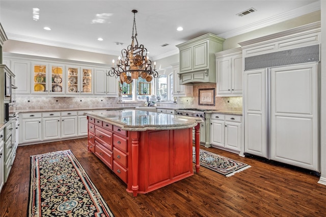 kitchen featuring high quality appliances, a center island, white cabinetry, dark hardwood / wood-style floors, and crown molding