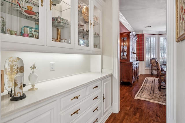 bar featuring white cabinets, crown molding, and dark hardwood / wood-style floors