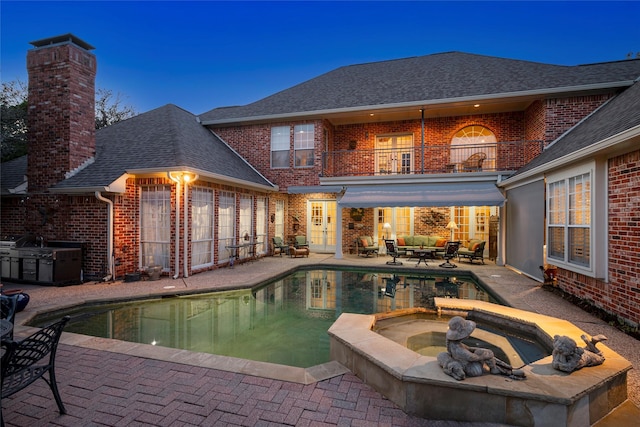 pool at dusk with a patio and an in ground hot tub