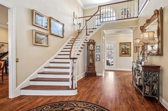 entryway with a towering ceiling, dark wood-type flooring, and crown molding