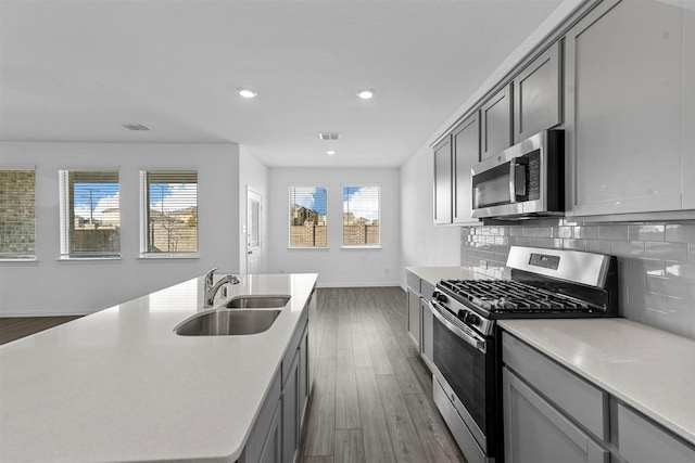 kitchen with stainless steel appliances, sink, gray cabinetry, tasteful backsplash, and a healthy amount of sunlight