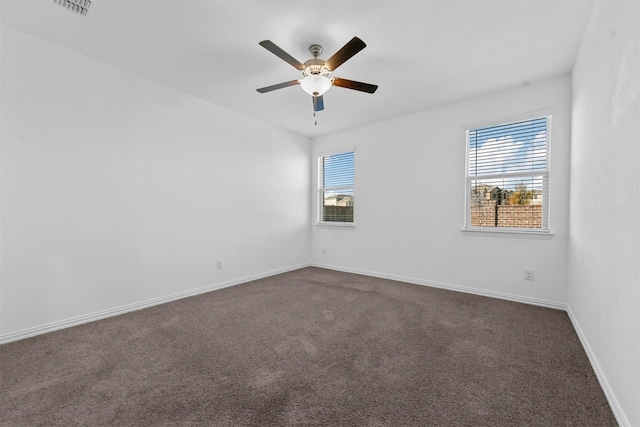 carpeted spare room featuring ceiling fan and a wealth of natural light