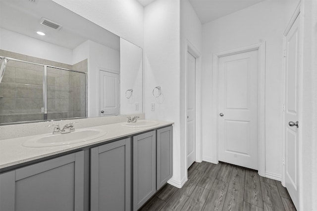 bathroom featuring wood-type flooring, a shower with door, and vanity