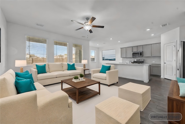 living room featuring dark wood-type flooring and ceiling fan