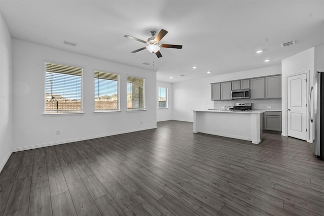 unfurnished living room with ceiling fan and dark hardwood / wood-style flooring