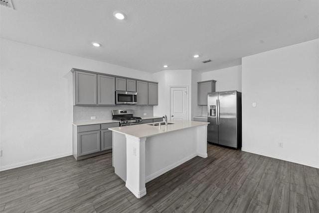 kitchen with sink, gray cabinetry, a center island with sink, appliances with stainless steel finishes, and dark hardwood / wood-style floors