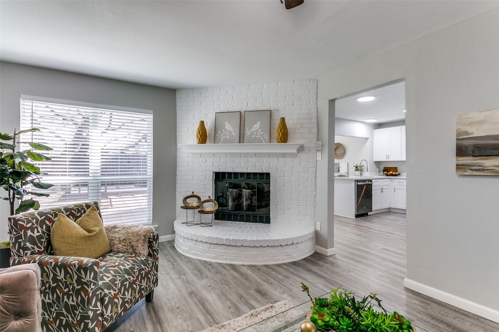 living room featuring a brick fireplace and wood-type flooring