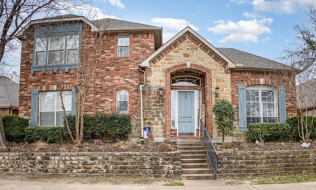 view of front of property with stone siding, brick siding, and roof with shingles