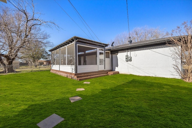 rear view of property featuring a sunroom and a yard